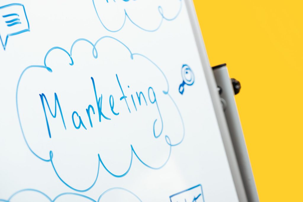 GO Get Organised blog - Marketing your business. Marketing written on whiteboard in blue pen, whiteboard on yellow background
